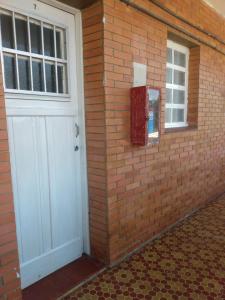 a brick wall with a white door and a window at Apto Central Barra de Imbé in Imbé