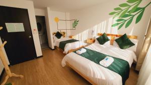 a bedroom with two beds with green and white sheets at Hotel Natural Sevgi in Bogotá