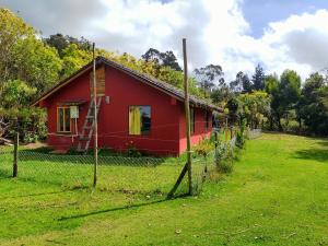 una casa roja con una valla delante en Ataraxia - Atarixa, en Subachoque