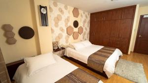 1 dormitorio con 2 camas y reloj en la pared en Hotel Ficoa, en Ambato