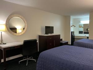 ein Hotelzimmer mit 2 Betten, einem Schreibtisch und einem Spiegel in der Unterkunft Garden Inn & Suites in Metter