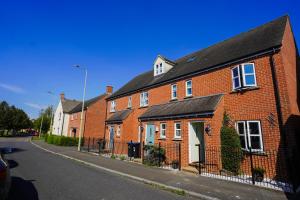 a row of brick houses on a street at Stunning Harvest Way House in Witney