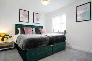 a bedroom with a green bed with pink pillows at Stunning Harvest Way House in Witney