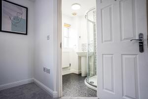 a bathroom with a shower and a white door at Stunning Harvest Way House in Witney