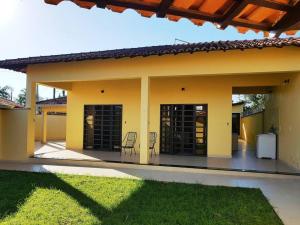 a yellow house with a patio with a table and chairs at Casa para Temporada em Cananéia in Cananéia