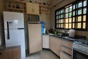 a kitchen with a refrigerator and a stove and windows at Casa para Temporada em Cananéia in Cananéia