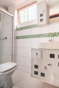 a white bathroom with a toilet and a sink at Apartamento de um quarto, próximo ao Estadual. in Bauru