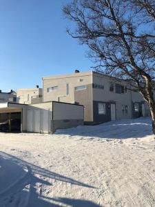 budynek w śniegu z drzewem przed nim w obiekcie Book an apartment just for you in central Tromsø w mieście Tromsø