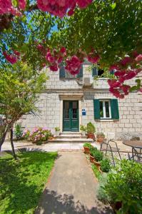 ein Steingebäude mit grüner Tür und rosa Blumen in der Unterkunft Apartments by the sea Dubrovnik - 20309 in Dubrovnik