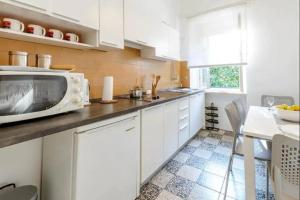 Apartments by the sea Dubrovnik - 20309 في دوبروفنيك: مطبخ مع دواليب بيضاء وميكرويف على كونتر
