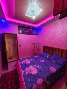 Un dormitorio con una cama con luces rosas. en Residence Anarouz - Sidi Ifni, en Sidi Ifni