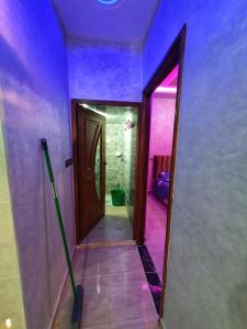 un couloir avec une porte menant à une salle de bains aux murs violets dans l'établissement Residence Anarouz - Sidi Ifni, à Sidi Ifni