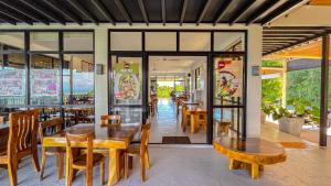 restauracja z drewnianymi stołami i krzesłami oraz oknami w obiekcie Villa Lorenzo @ Caliraya Heights Resorts w mieście Halang