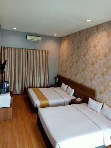 Habitación de hotel con 2 camas y ventana en Surya Palace Syariah en Padang