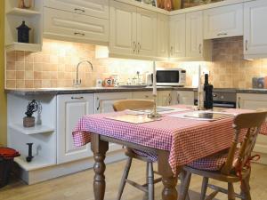 a kitchen with a table with a checkered table cloth on it at Old Barn Cottage in Lockton
