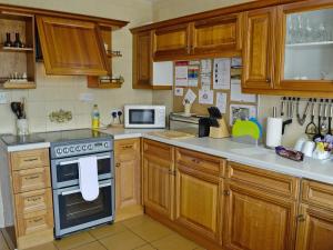 a kitchen with wooden cabinets and a stove top oven at Tir Nani Ogg in Kinmel Bay