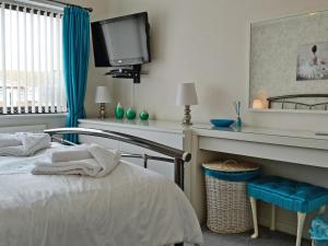 a bedroom with a bed and a tv on the wall at Tir Nani Ogg in Kinmel Bay