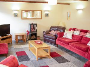 a living room with red couches and a tv at Little Content Farm Cottage in Cury