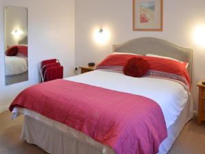 a bedroom with a large bed with a pink blanket at Little Content Farm Cottage in Cury