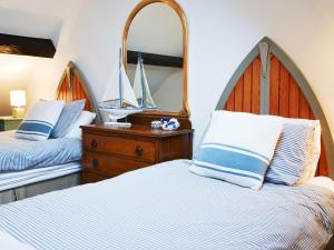 a bedroom with two beds and a dresser with a mirror at Clutter Cottage in Widdrington