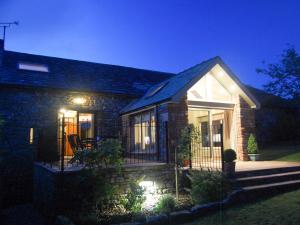 a brick house with a porch at night at Garden Cottage in Pooley Bridge