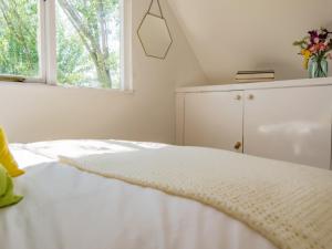 a white bedroom with a bed and a window at Mitford Lodge in Wye