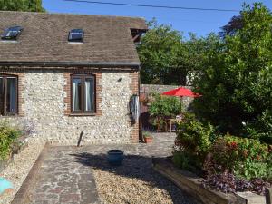 a stone cottage with a patio and a red umbrella at Darwin Cottage - E4509 in Jevington