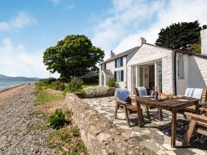 a table and chairs sitting outside of a cottage at Blue Sails-jpv in Llangoed