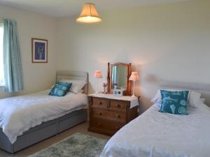 a bedroom with two beds and a dresser with a mirror at Seafield in Llanrhyddlad