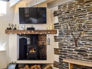 a living room with a fireplace and a tv on a stone wall at The Old Chapel in Washaway