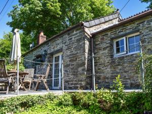 a stone cottage with a patio and an umbrella at The Old Chapel in Washaway
