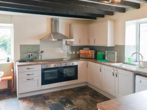 a kitchen with white cabinets and a sink at Hen Ysgol in Llanfaethlu