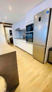 a kitchen with a stainless steel refrigerator and wooden floors at Aux vents des rhums au cœur de la Marina du Gosier avec vue imprenable in Pointe-à-Pitre