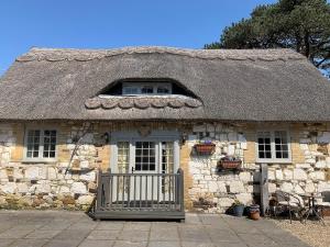 a small stone house with a thatched roof at Brixton Barn in Mottistone