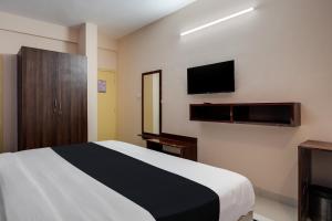 1 dormitorio con 1 cama y TV de pantalla plana en Super Collection O Veritas Grand, en Bangalore