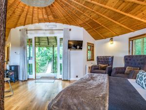 a bedroom with a bed and a couch and chairs at Bensfield Treehouse in Wadhurst