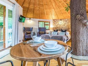 uma sala de jantar com uma mesa com pratos e copos de vinho em Bensfield Treehouse em Wadhurst
