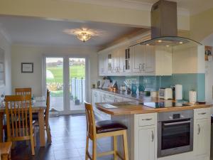 a kitchen with white cabinets and a table with chairs at Seaward in Portpatrick