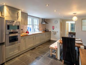 a large kitchen with stainless steel appliances and a table at Catstycam in Thirlmere