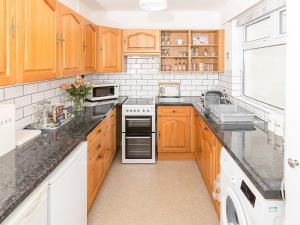 una cocina con armarios de madera y encimeras negras en Bosorne, en Newlyn