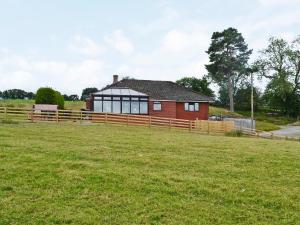een rood huis met een hek en een grasveld bij Bryn Villa in Newbridge on Wye