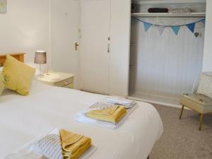 Un dormitorio con una cama blanca con toallas. en Bosorne, en Newlyn