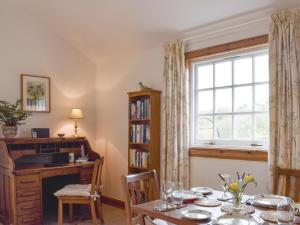 a dining room with a table and a window at Lucklaw Steading Cottage in Logie