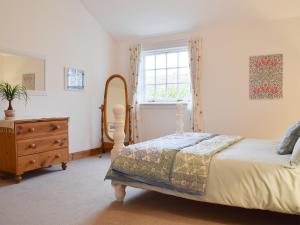 a bedroom with a bed and a dresser and a window at Lucklaw Steading Cottage in Logie