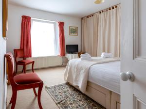 a bedroom with a bed and a chair and a window at Windward House in Salcombe
