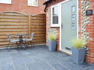 a patio with a table and chairs next to a garage at Willow Cottage in Great Ryburgh