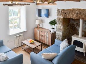 a living room with blue chairs and a stone fireplace at Bryn Awel in Moelfre