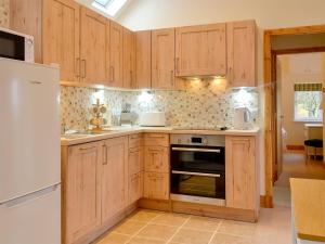 a kitchen with wooden cabinets and a white refrigerator at The Old Inverchroskie Kennels in Enochdhu