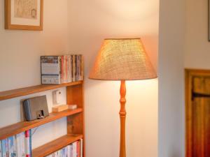 una lámpara en una esquina de una habitación con estantería en Gowan Bank Farm Cottage en Staveley