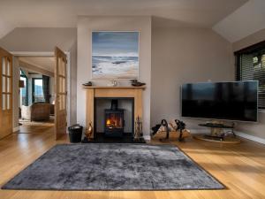 a living room with a fireplace and a flat screen tv at Kyles View in Ollach